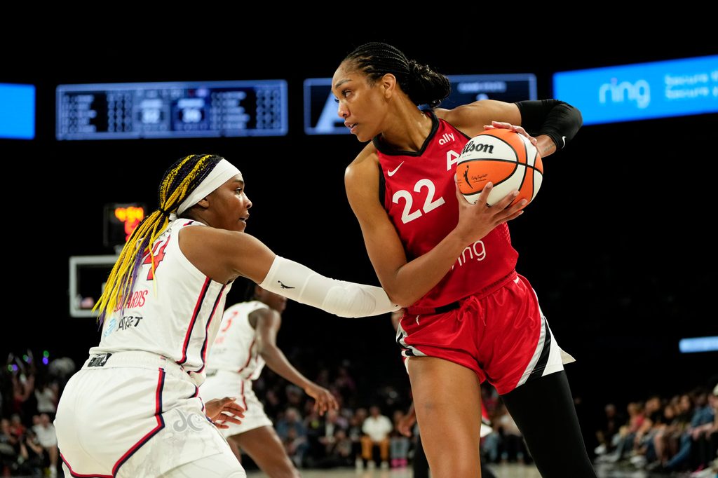 Jun 26, 2025; Las Vegas, Nevada, USA; Las Vegas Aces center A'ja Wilson (22) controls the ball against Washington Mystics forward Aaliyah Edwards (24) during the first half of a WNBA basketball game at Michelob Ultra Arena. Mandatory Credit: Lucas Peltier-Imagn Images