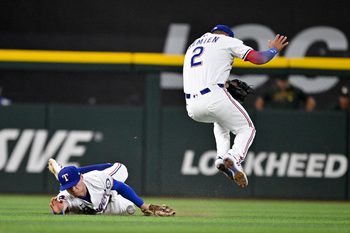 Jul 23, 2025; Arlington, Texas, USA; Texas Rangers center fielder Michael Helman (24) dives but cannot catch a ball hit by Athletics left fielder Miguel Andujar (not pictured) as second baseman Marcus Semien (2) attempts to get out of way during the sixth inning at Globe Life Field. Mandatory Credit: Jerome Miron-Imagn Images