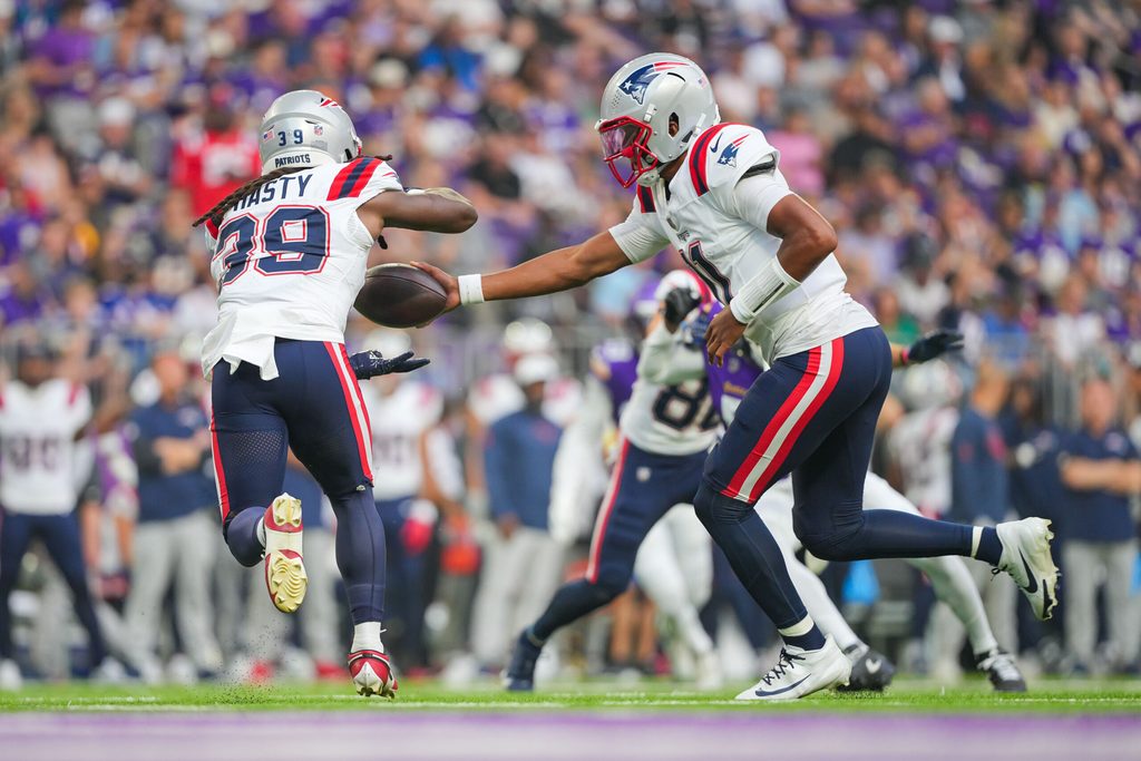 Aug 16, 2025; Minneapolis, Minnesota, USA; New England Patriots quarterback Joshua Dobbs (11) hands the ball off to running back JaMycal Hasty (39) against the Minnesota Vikings in the second quarter at U.S. Bank Stadium. Mandatory Credit: Brad Rempel-Imagn Images