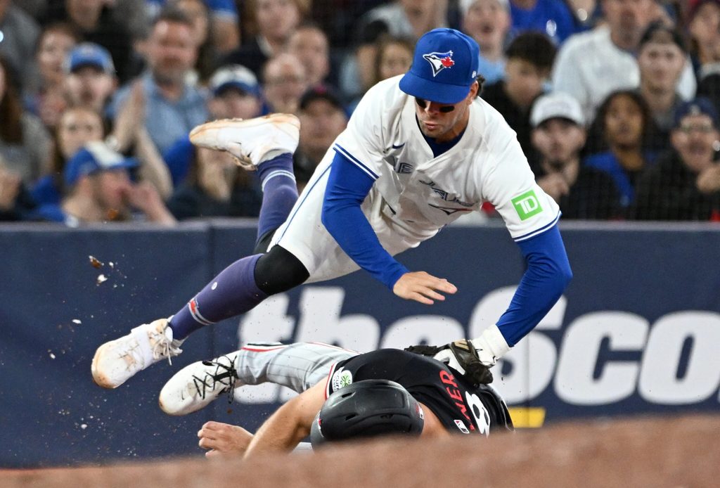 Aug 26, 2025; Toronto, Ontario, CAN; Toronto Blue Jays third baseman Ernie Clement (22) is upended after tagging out Minnesota Twins right fielder Matt Wallner (38) in the eighth inning at Rogers Centre. Mandatory Credit: Dan Hamilton-Imagn Images