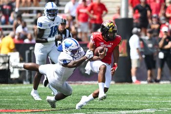 Sep 3, 2022; College Park, Maryland, USA;  Buffalo Bulls wide receiver Jovany Ruiz-Navarro (8) tackles Maryland Terrapins quarterback Taulia Tagovailoa (3) during the first half at Capital One Field at Maryland Stadium. Mandatory Credit: Tommy Gilligan-Imagn Images