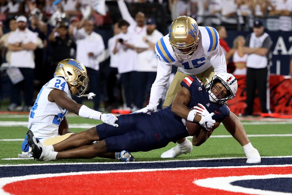 Nov 4, 2023; Tucson, Arizona, USA; Arizona Wildcats wide receiver Montana Lemonious-Craig #5 dives into the endzone against UCLA Bruins defensive back Jaylin Davies #24 and defensive lineman Laiatu Latu #15  during the first half at Arizona Stadium. Mandatory Credit: Zachary BonDurant-Imagn Images