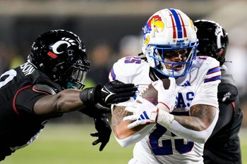 Kansas Jayhawks running back Dylan McDuffie (25) guards the ball from ensuing Cincinnati Bearcats as he runs down the field during the NCAA college football game between the Cincinnati Bearcats and Kansas Jayhawks on Saturday, Nov. 25, 2023, at Nippert Stadium in Cincinnati. Kansas won 49-16.