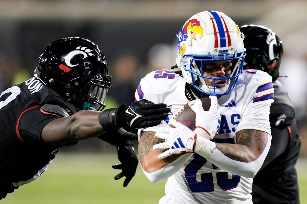 Kansas Jayhawks running back Dylan McDuffie (25) guards the ball from ensuing Cincinnati Bearcats as he runs down the field during the NCAA college football game between the Cincinnati Bearcats and Kansas Jayhawks on Saturday, Nov. 25, 2023, at Nippert Stadium in Cincinnati. Kansas won 49-16.