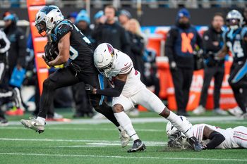 Dec 22, 2024; Charlotte, North Carolina, USA; Carolina Panthers running back Chuba Hubbard (30) tries to evade Arizona Cardinals safety Jalen Thompson (34) during the second half at Bank of America Stadium. Mandatory Credit: Jim Dedmon-Imagn Images