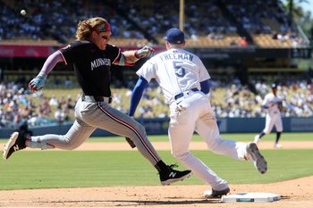 Jul 23, 2025; Los Angeles, California, USA;  Minnesota Twins pinch hitter Harrison Bader (12) beats the throw to Los Angeles Dodgers first baseman Freddie Freeman (5) for an RBI single during the eighth inning at Dodger Stadium. Mandatory Credit: Kiyoshi Mio-Imagn Images