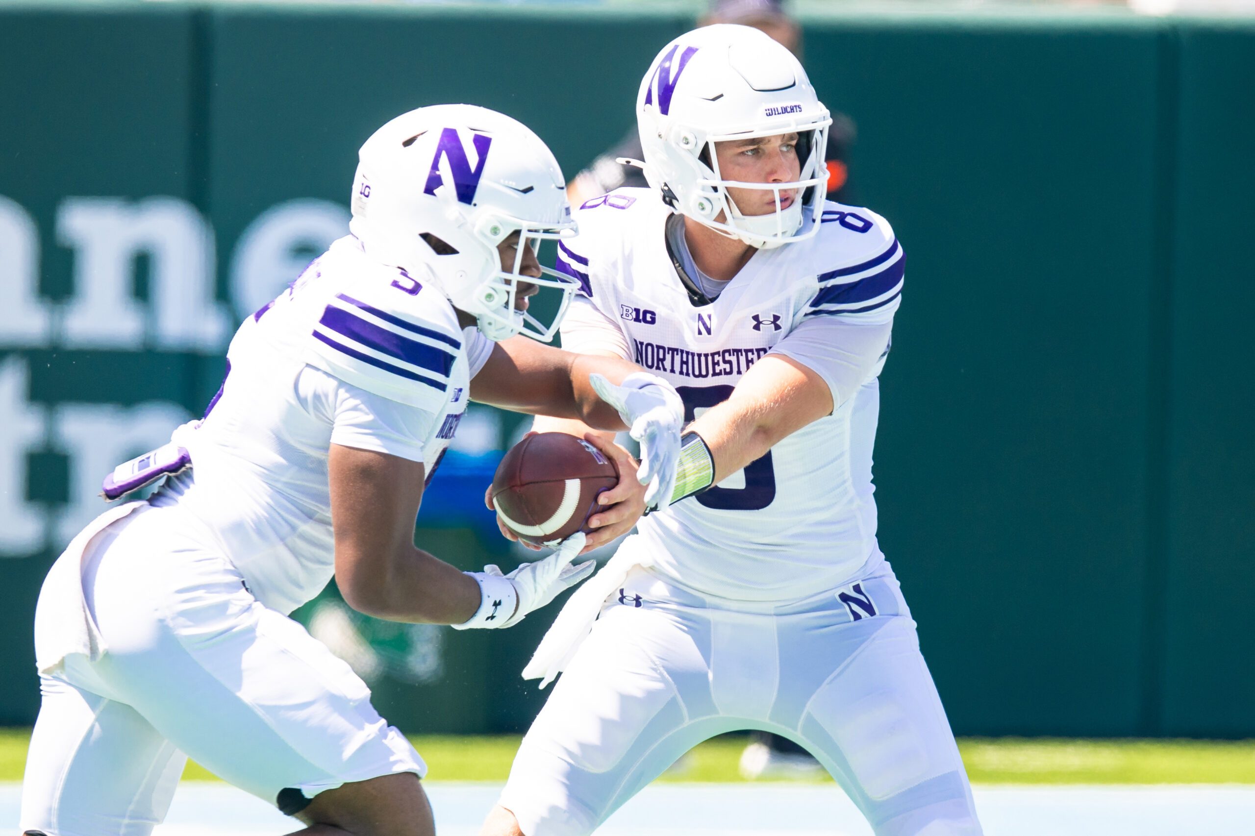 Aug 30, 2025; New Orleans, Louisiana, USA;  Northwestern Wildcats quarterback Preston Stone (8) hands the ball off to running back Caleb Komolafe (5) against Tulane Green Wave during the second half at Yulman Stadium. Mandatory Credit: Stephen Lew-Imagn Images