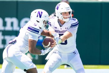 Aug 30, 2025; New Orleans, Louisiana, USA;  Northwestern Wildcats quarterback Preston Stone (8) hands the ball off to running back Caleb Komolafe (5) against Tulane Green Wave during the second half at Yulman Stadium. Mandatory Credit: Stephen Lew-Imagn Images