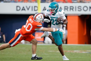Aug 30, 2025; Charlottesville, Virginia, USA; Coastal Carolina Chanticleers running back Dominic Knicely (23) carries the ball as Virginia Cavaliers safety Ethan Minter (30) during the second quarter at Scott Stadium. Mandatory Credit: Amber Searls-Imagn Images