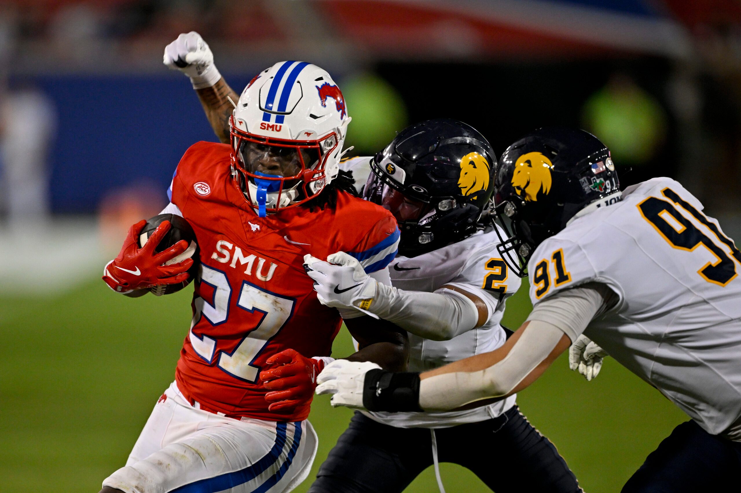 Aug 30, 2025; Dallas, Texas, USA; Southern Methodist Mustangs running back T.J. Harden (27) is tackled by East Texas A&M Lions defensive back Lavon Williams (2) and defensive lineman Micah Johnson (91) during the second half at Gerald J. Ford Stadium. Mandatory Credit: Jerome Miron-Imagn Images