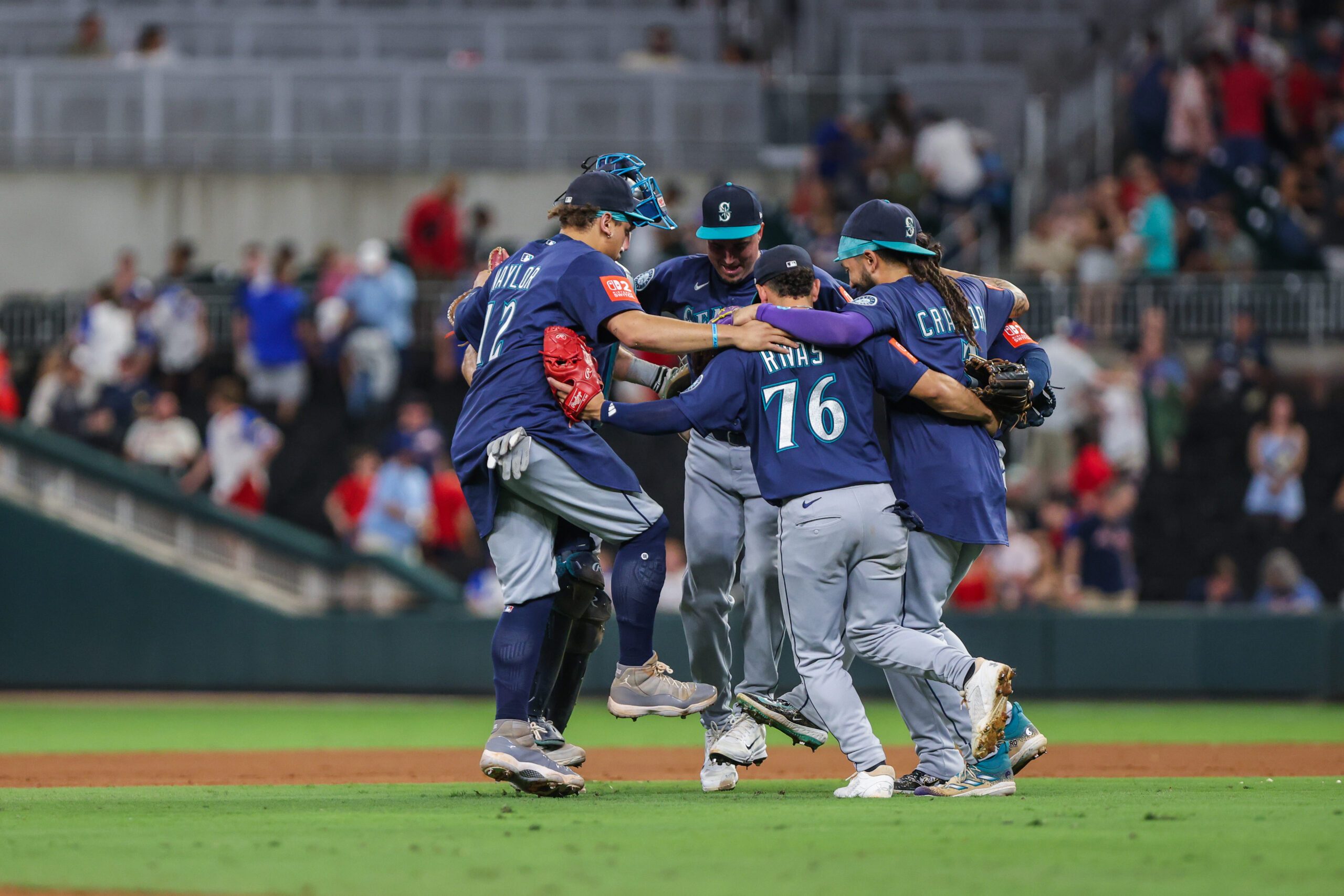 Sep 6, 2025; Cumberland, Georgia, USA; Seattle Mariners catcher Cal Raleigh (29), first base Josh Naylor (12), second base Leo Rivas (76), and shortstop J.P. Crawford (3) celebrate a victory against the Atlanta Braves after the game at Truist Park. Mandatory Credit: Jordan Godfree-Imagn Images