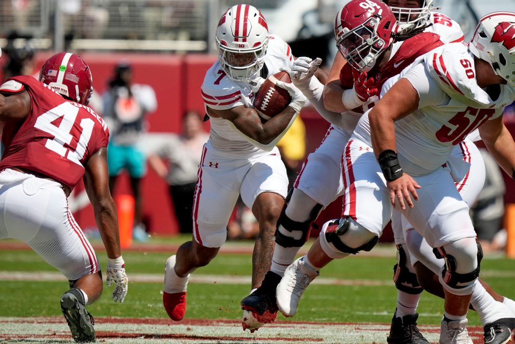 Sep 13, 2025; Tuscaloosa, Alabama, USA; Wisconsin running back Dilin Jones (7) runs the ball between Alabama linebacker Nikhai Hill-Green (41) and Alabama defensive lineman Edric Hill (94) at Saban Field at Bryant-Denny Stadium. Mandatory Credit: Gary Cosby-USA TODAY Network via Imagn Images