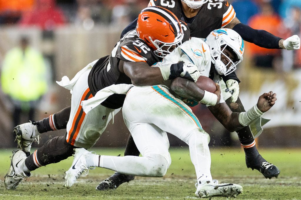 Dec 29, 2024; Cleveland, Ohio, USA; Cleveland Browns defensive end Sam Kamara (92) tackles Miami Dolphins quarterback Tyler Huntley (18) during the fourth quarter at Huntington Bank Field. Mandatory Credit: Scott Galvin-Imagn Images