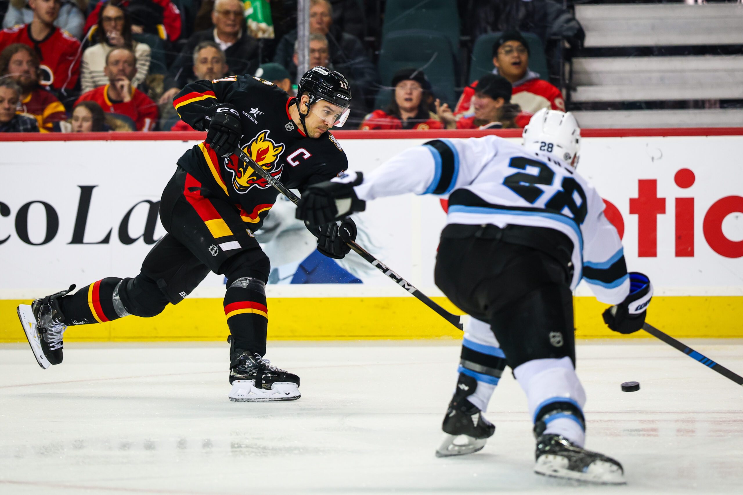 Jan 2, 2025; Calgary, Alberta, CAN; Calgary Flames center Mikael Backlund (11) shoots the puck against the Utah Hockey Club during the third period at Scotiabank Saddledome. Mandatory Credit: Sergei Belski-Imagn Images