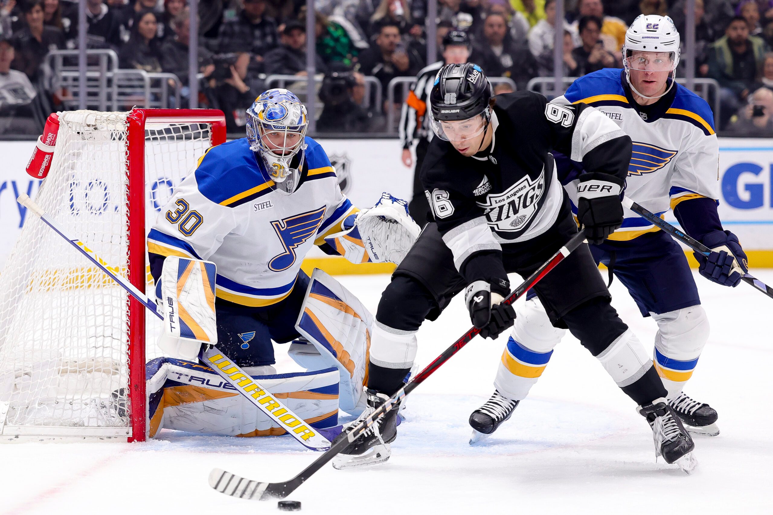 Mar 8, 2025; Los Angeles, California, USA; Los Angeles Kings left wing Andrei Kuzmenko (96) looks to shoot ahead of St. Louis Blues defenseman Ryan Suter (22) and goaltender Joel Hofer (30) during the second period at Crypto.com Arena. Mandatory Credit: Ryan Sun-Imagn Images