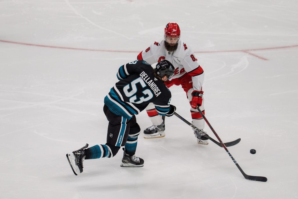 Mar 20, 2025; San Jose, California, USA; San Jose Sharks center Ty Dellandrea (53) shoots the puck against Carolina Hurricanes defenseman Brent Burns (8) during the third period at SAP Center at San Jose. Mandatory Credit: Neville E. Guard-Imagn Images