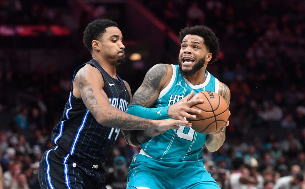 Mar 25, 2025; Charlotte, North Carolina, USA; Charlotte Hornets forward Miles Bridges (0) looks to pass as he is defended by Orlando Magic guard Gary Harris (14) during the second half at the Spectrum Center. Mandatory Credit: Sam Sharpe-Imagn Images