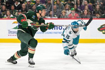 Apr 9, 2025; Saint Paul, Minnesota, USA;  Minnesota Wild forward Joel Eriksson Ek (14) scores his fourth goal of the night as San Jose Sharks forward Nikolai Kovalenko (15) defends during the third period at Xcel Energy Center. Mandatory Credit: Nick Wosika-Imagn Images