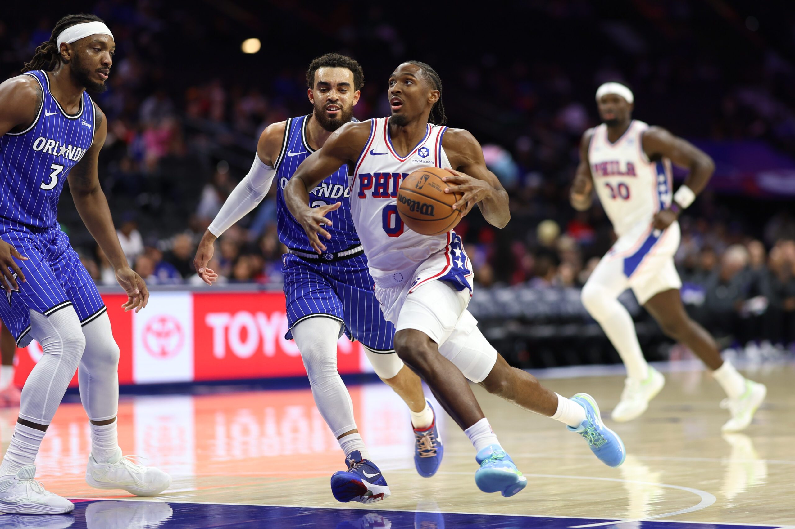 Oct 10, 2025; Philadelphia, Pennsylvania, USA; Philadelphia 76ers guard Tyrese Maxey (0) drives past Orlando Magic guard Tyus Jones (2) during the first quarter at Xfinity Mobile Arena. Mandatory Credit: Bill Streicher-Imagn Images