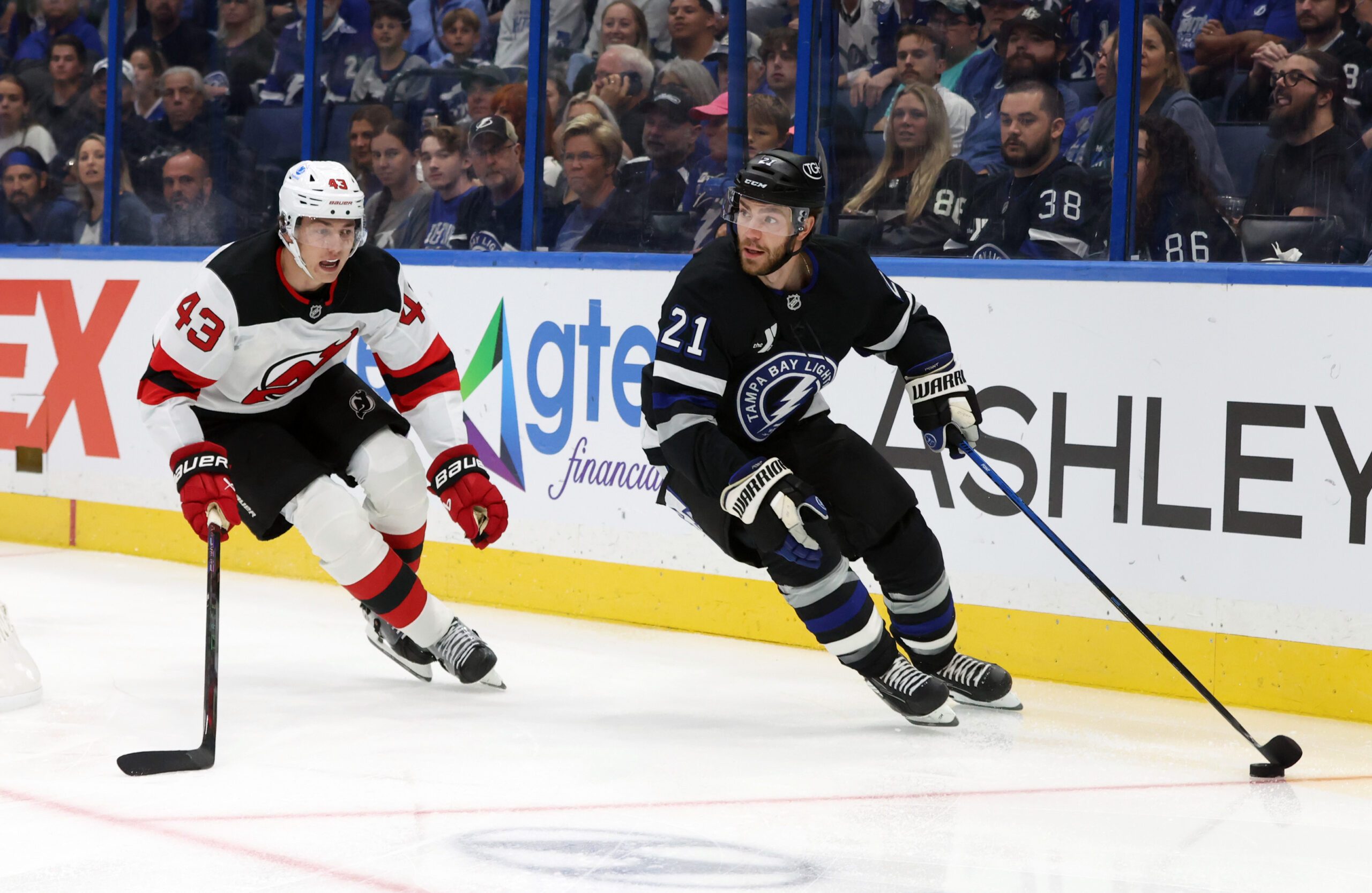 Oct 11, 2025; Tampa, Florida, USA; Tampa Bay Lightning center Brayden Point (21)] skates with the puck as New Jersey Devils defenseman Luke Hughes (43) defends during the first period at Benchmark International Arena. Mandatory Credit: Kim Klement Neitzel-Imagn Images