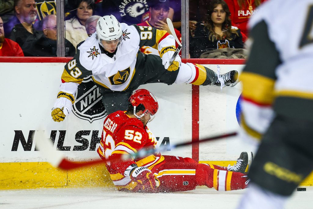 Oct 14, 2025; Calgary, Alberta, CAN; Calgary Flames defenseman Mackenzie Weegar (52) and Vegas Golden Knights right wing Mitch Marner (93) battles for the puck during the third period at Scotiabank Saddledome. Mandatory Credit: Sergei Belski-Imagn Images