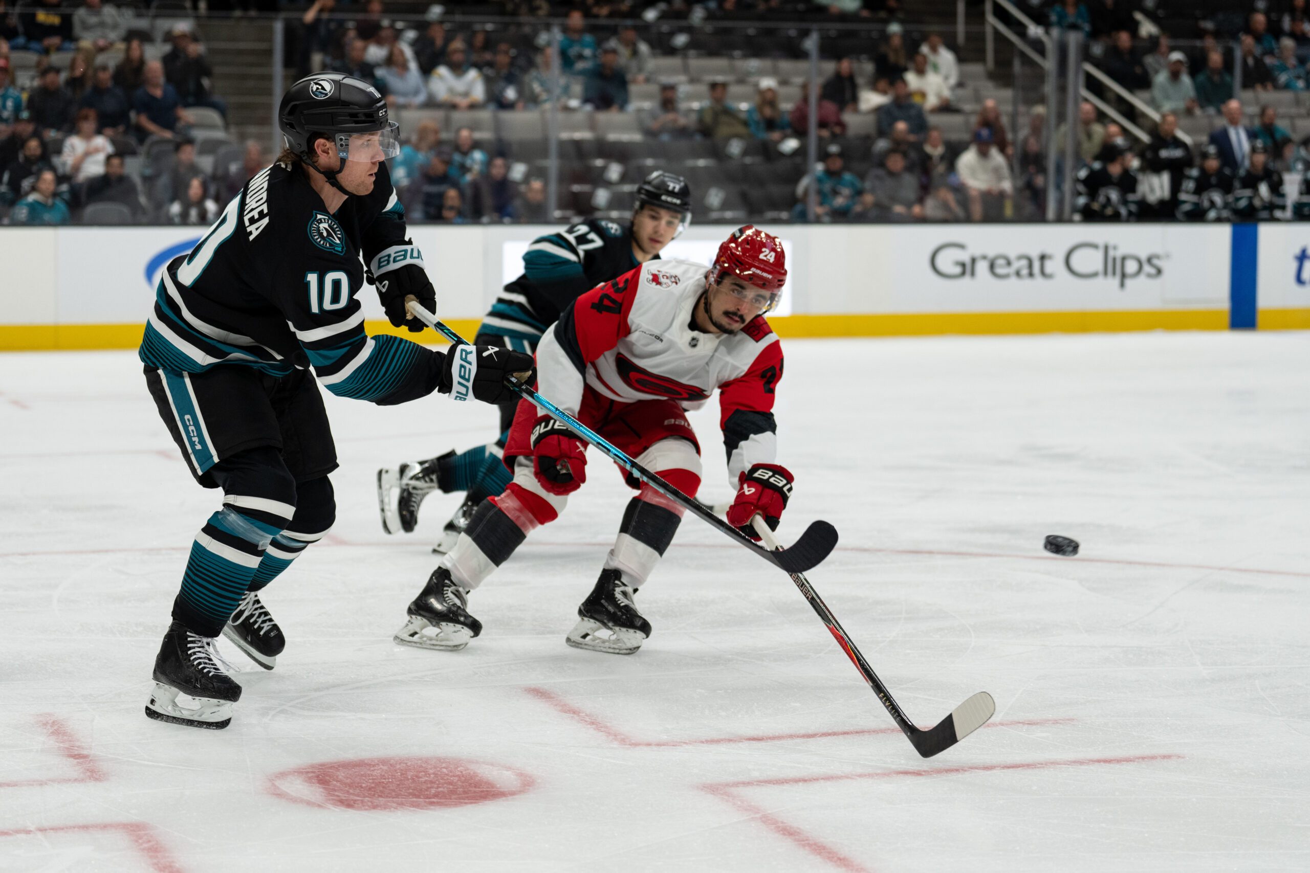 Oct 14, 2025; San Jose, California, USA;  San Jose Sharks center Ty Dellandrea (10) shoots the puck past Carolina Hurricanes center Seth Jarvis (24) during the first period at SAP Center at San Jose. Mandatory Credit: Stan Szeto-Imagn Images