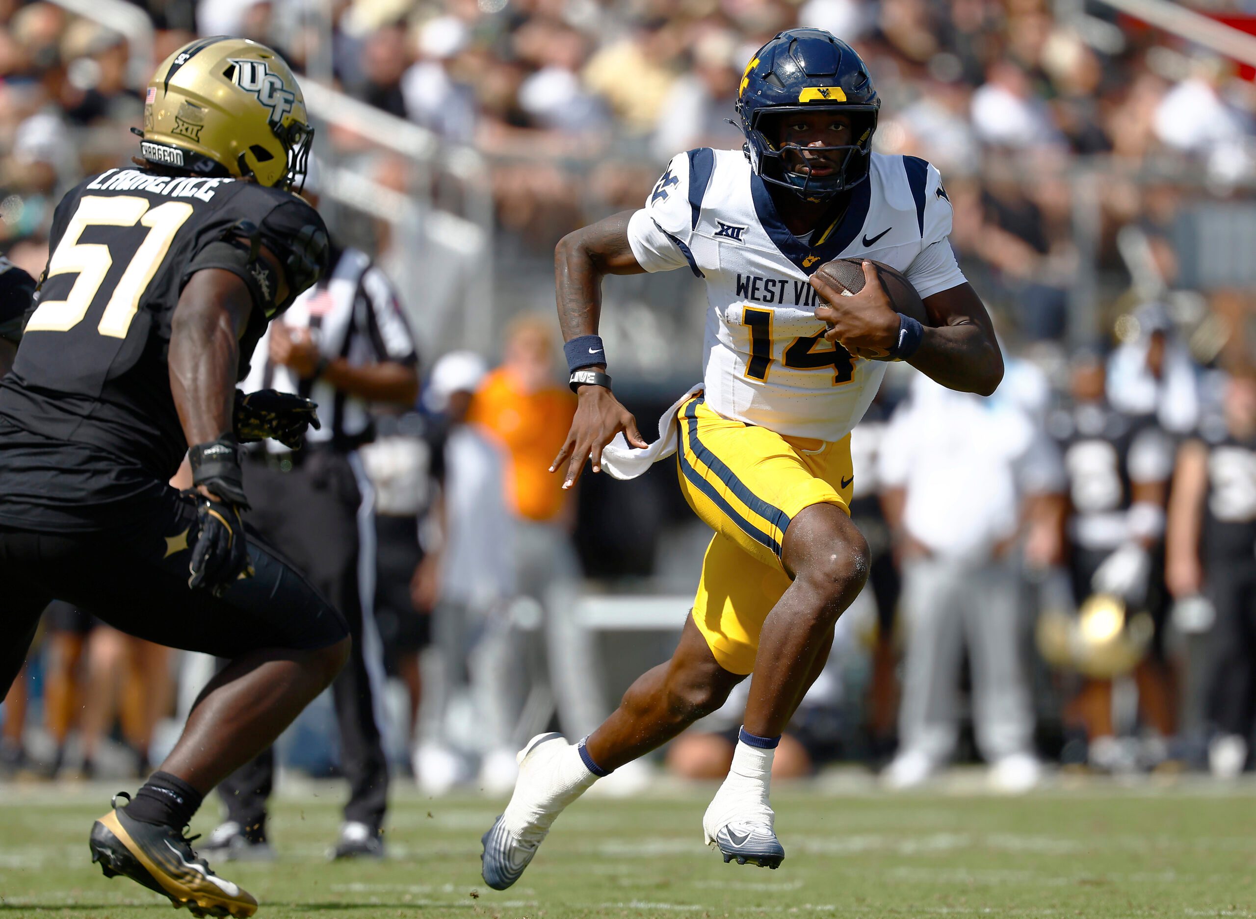 Oct 18, 2025; Orlando, Florida, USA; West Virginia Mountaineers quarterback Khalil Wilkins (14) runs the ball for a touchdown in the first half against the Central Florida Knights at Acrisure Bounce House. Mandatory Credit: Russell Lansford-Imagn Images