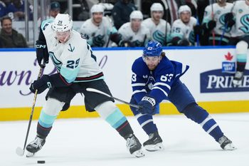 Oct 18, 2025; Toronto, Ontario, CAN; Seattle Kraken defenseman Vince Dunn (29) controls the puck defended by Toronto Maple Leafs left wing Matias MacCelli (63) during the third period at Scotiabank Arena. Mandatory Credit: Nick Turchiaro-Imagn Images