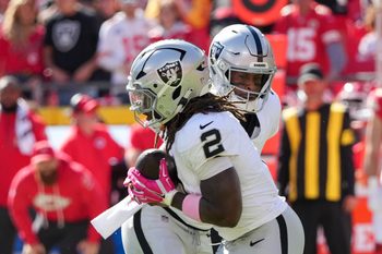 Oct 19, 2025; Kansas City, Missouri, USA; Las Vegas Raiders quarterback Geno Smith (7) hands the ball to Las Vegas Raiders running back Ashton Jeanty (2) against the Kansas City Chiefs during the second quarter of the game at GEHA Field at Arrowhead Stadium. Mandatory Credit: Denny Medley-Imagn Images