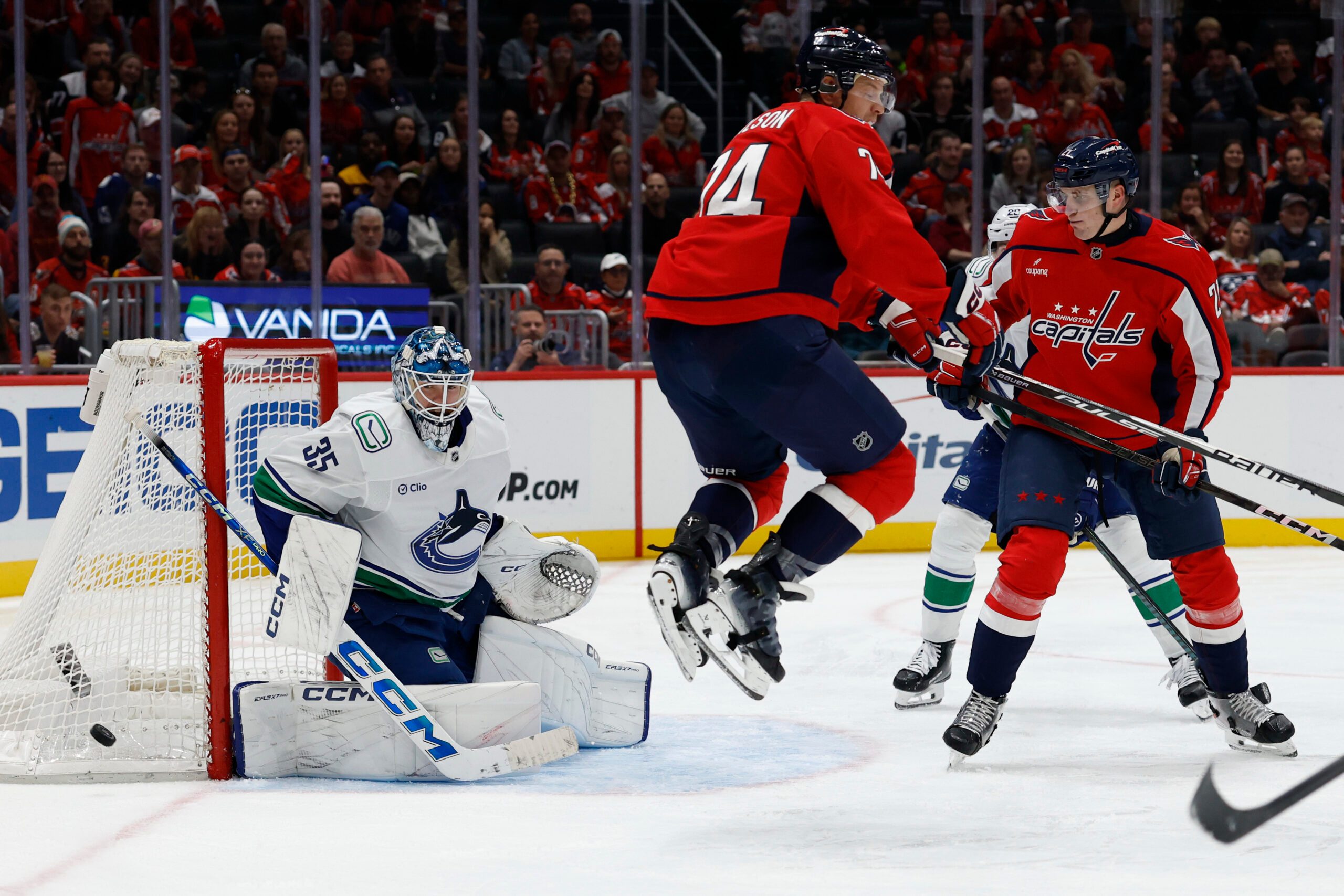 Oct 19, 2025; Washington, District of Columbia, USA; Vancouver Canucks goaltender Thatcher Demko (35) makes a save in front of Washington Capitals defenseman John Carlson (74) and Capitals center Aliaksei Protas (21) during the third period at Capital One Arena. Mandatory Credit: Geoff Burke-Imagn Images