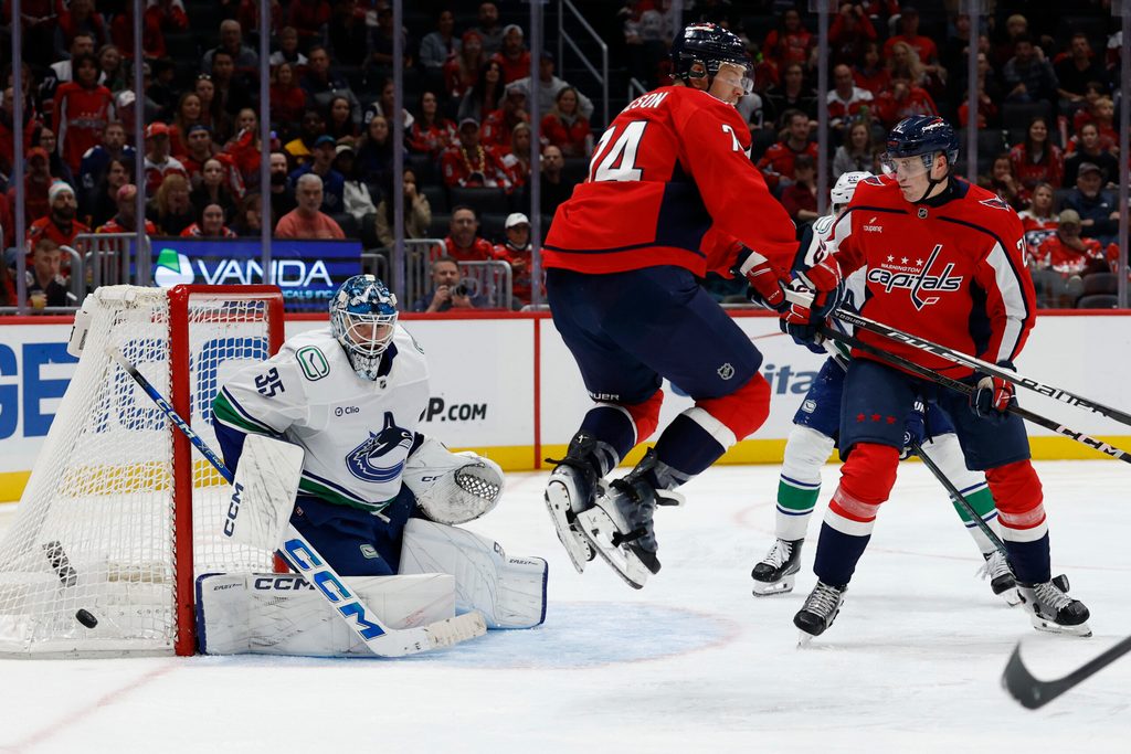 Oct 19, 2025; Washington, District of Columbia, USA; Vancouver Canucks goaltender Thatcher Demko (35) makes a save in front of Washington Capitals defenseman John Carlson (74) and Capitals center Aliaksei Protas (21) during the third period at Capital One Arena. Mandatory Credit: Geoff Burke-Imagn Images