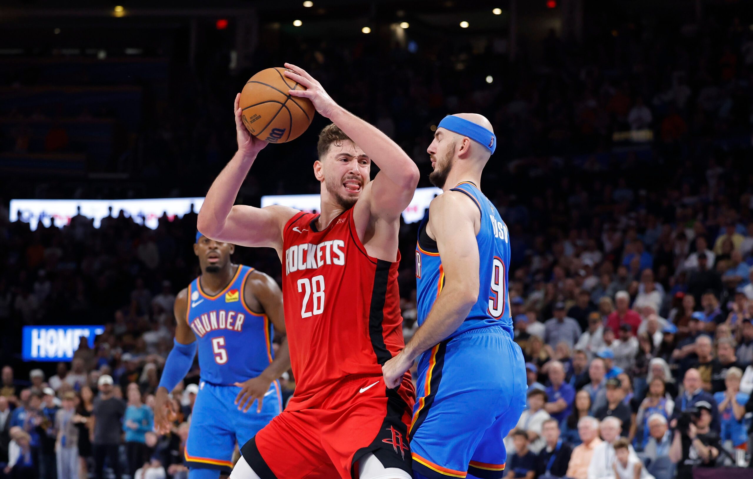 Oct 21, 2025; Oklahoma City, Oklahoma, USA; Houston Rockets center Alperen Sengun (28) drives against Oklahoma City Thunder guard Alex Caruso (9) during overtime at Paycom Center. Mandatory Credit: Alonzo Adams-Imagn Images