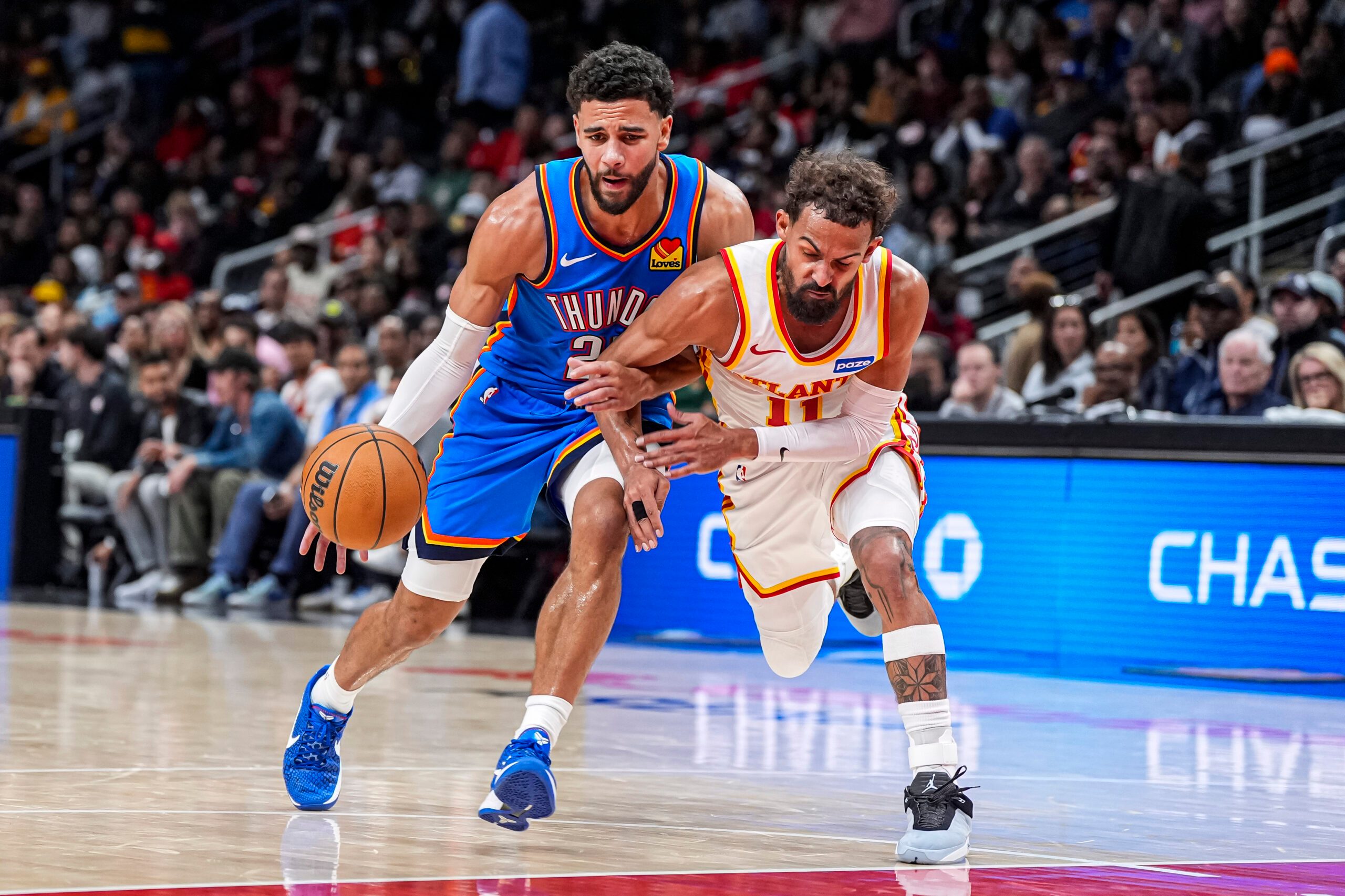 Oct 25, 2025; Atlanta, Georgia, USA; Oklahoma City Thunder guard Ajay Mitchell (25) tries to dribble past Atlanta Hawks guard Trae Young (11) during the second half at State Farm Arena. Mandatory Credit: Dale Zanine-Imagn Images