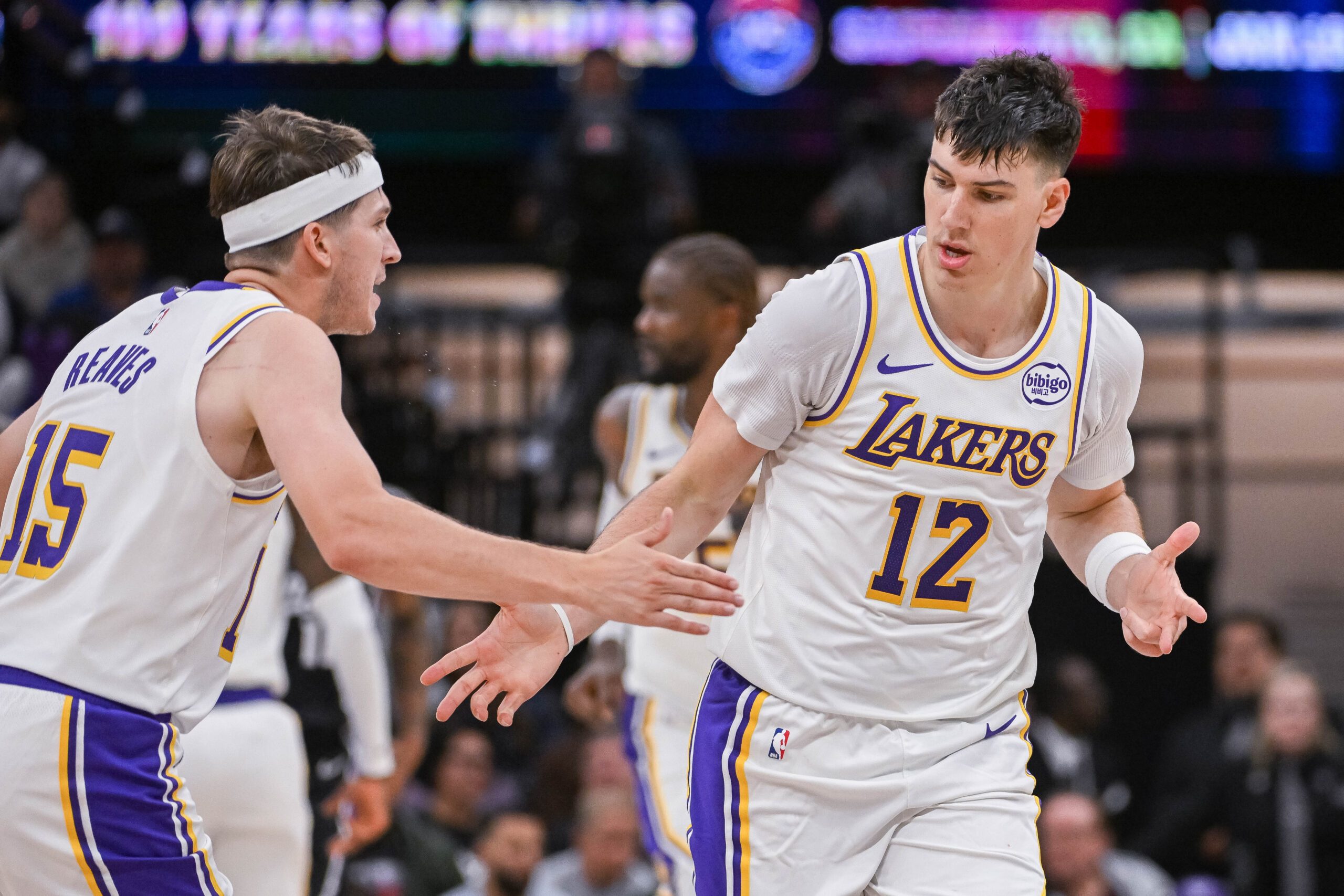 Oct 26, 2025; Sacramento, California, USA; Los Angeles Lakers forward Jake Laravia (12) high fives guard Austin Reaves (15) after scoring against the Sacramento Kings during the fourth quarter at Golden 1 Center. Mandatory Credit: Ed Szczepanski-Imagn Images