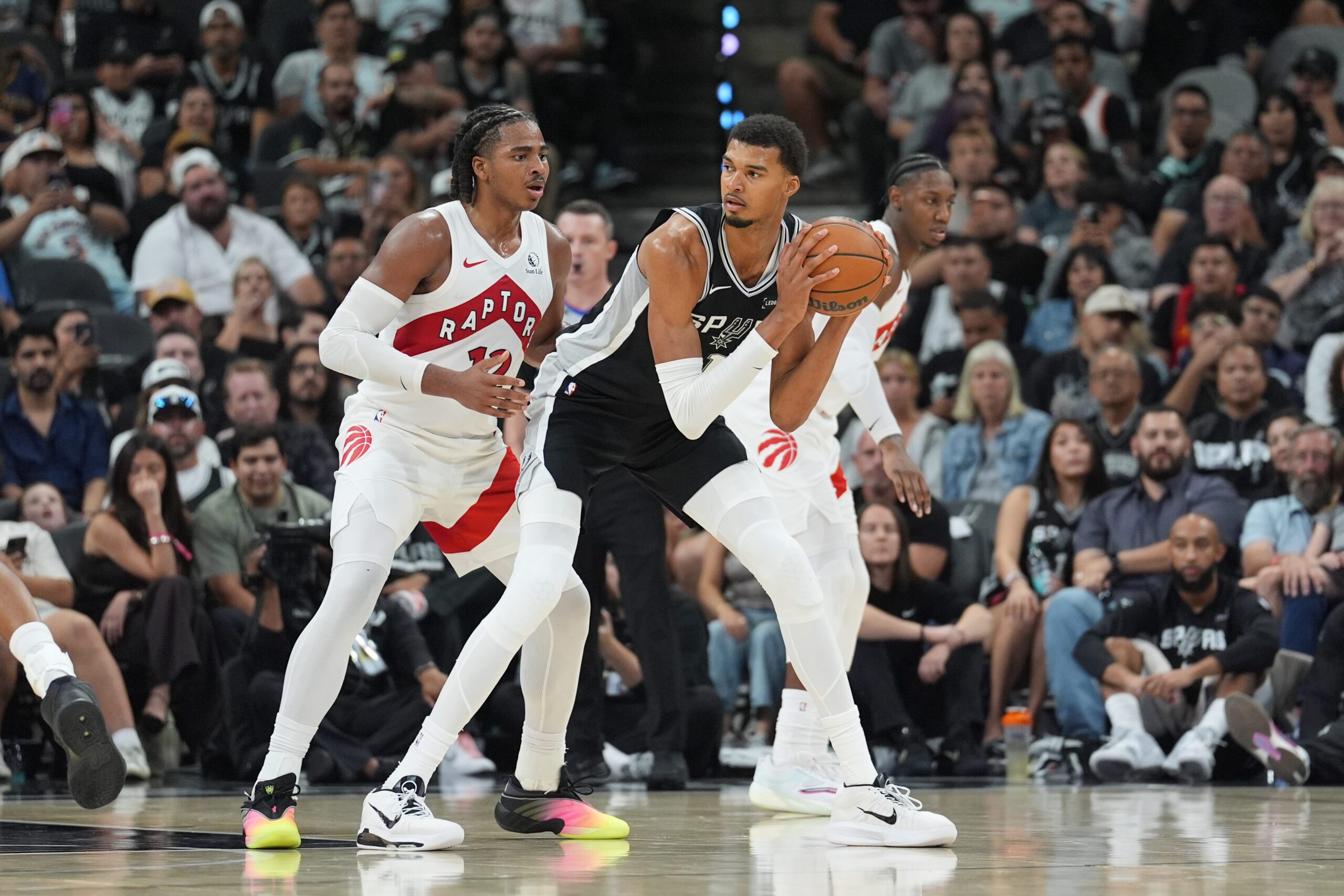 Oct 27, 2025; San Antonio, Texas, USA;  San Antonio Spurs forward/center Victor Wembanyama (1) looks to pass in front of Toronto Raptors forward Collin Murray-Boyles (12) in the second half at Frost Bank Center. Mandatory Credit: Daniel Dunn-Imagn Images