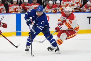 Oct 28, 2025; Toronto, Ontario, CAN; Toronto Maple Leafs forward Max Domi (11) controls the puck against Calgary Flames forward Jonathan Huberdeau (10) during the first period at Scotiabank Arena. Mandatory Credit: John E. Sokolowski-Imagn Images