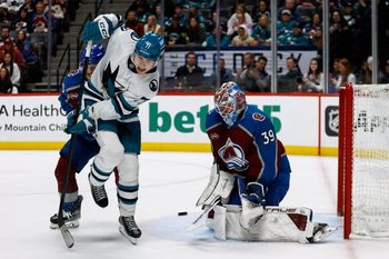 Mar 6, 2025; Denver, Colorado, USA; San Jose Sharks center Macklin Celebrini (71) attempts to deflect the puck against Colorado Avalanche goaltender Mackenzie Blackwood (39) as defenseman Ryan Lindgren (55) defends in the third period at Ball Arena. Mandatory Credit: Isaiah J. Downing-Imagn Images