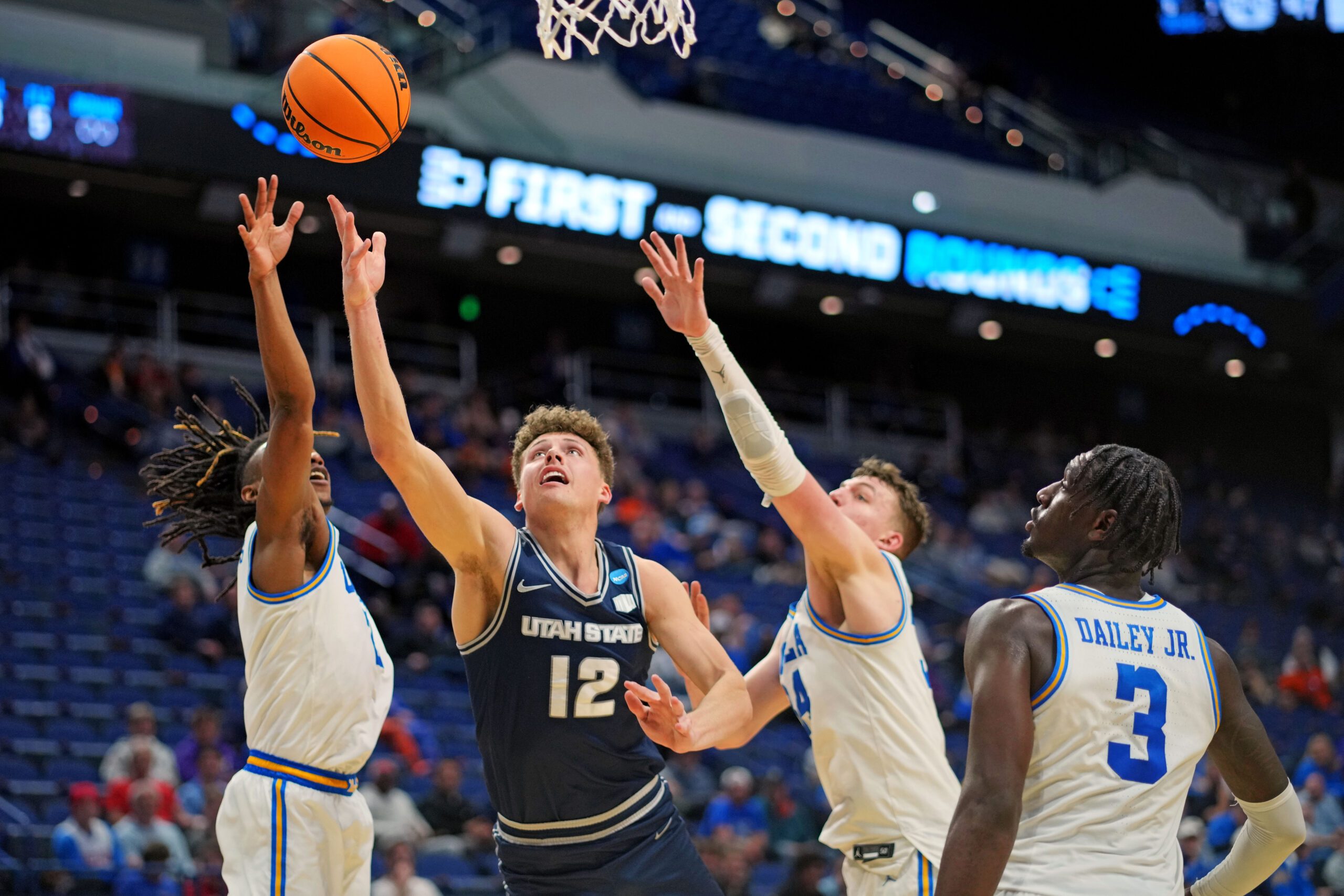 Mar 20, 2025; Lexington, KY, USA;  Utah State Aggies guard Mason Falslev (12) shoots the ball against UCLA Bruins forward Tyler Bilodeau (34) during the second half in the first round of the NCAA Tournament at Rupp Arena. Mandatory Credit: Aaron Doster-Imagn Images