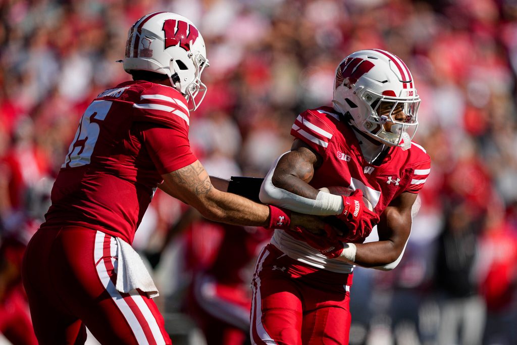 Oct 18, 2025; Madison, Wisconsin, USA; Wisconsin Badgers quarterback Hunter Simmons (15) hands the football off to running back Dilin Jones (7) during the game against the Ohio State Buckeyes at Camp Randall Stadium. Mandatory Credit: Jeff Hanisch-Imagn Images