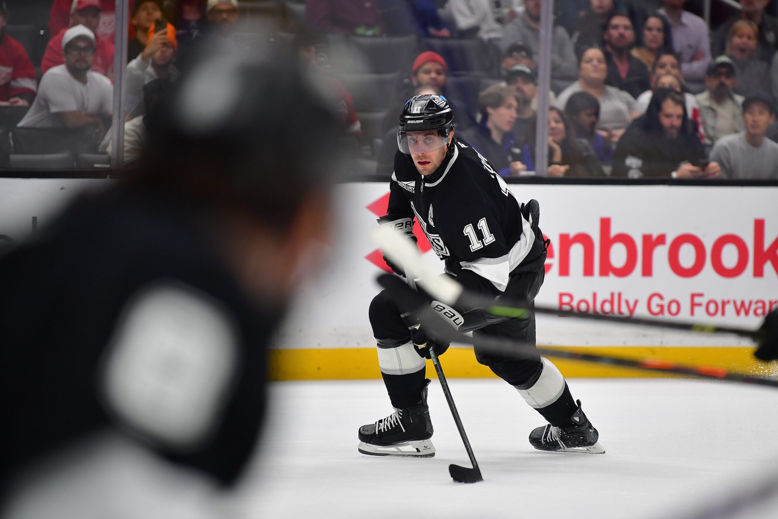 Oct 30, 2025; Los Angeles, California, USA; Los Angeles Kings center Anze Kopitar (11) moves the puck against the Detroit Red Wings during the overtime period at Crypto.com Arena. Mandatory Credit: Gary A. Vasquez-Imagn Images