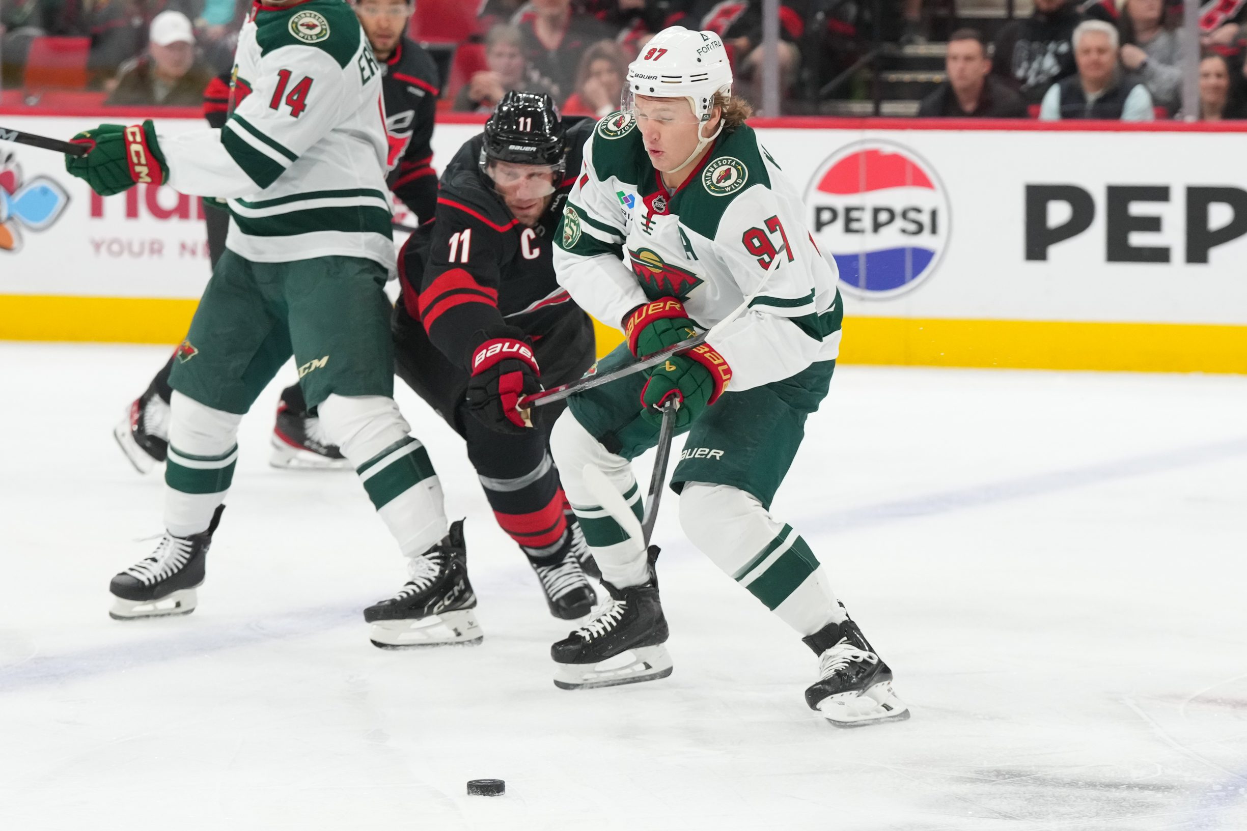 Nov 6, 2025; Raleigh, North Carolina, USA;  Minnesota Wild left wing Kirill Kaprizov (97) skates wwsith the puck inside of Carolina Hurricanes center Jordan Staal (11) during the first period at Lenovo Center. Mandatory Credit: James Guillory-Imagn Images