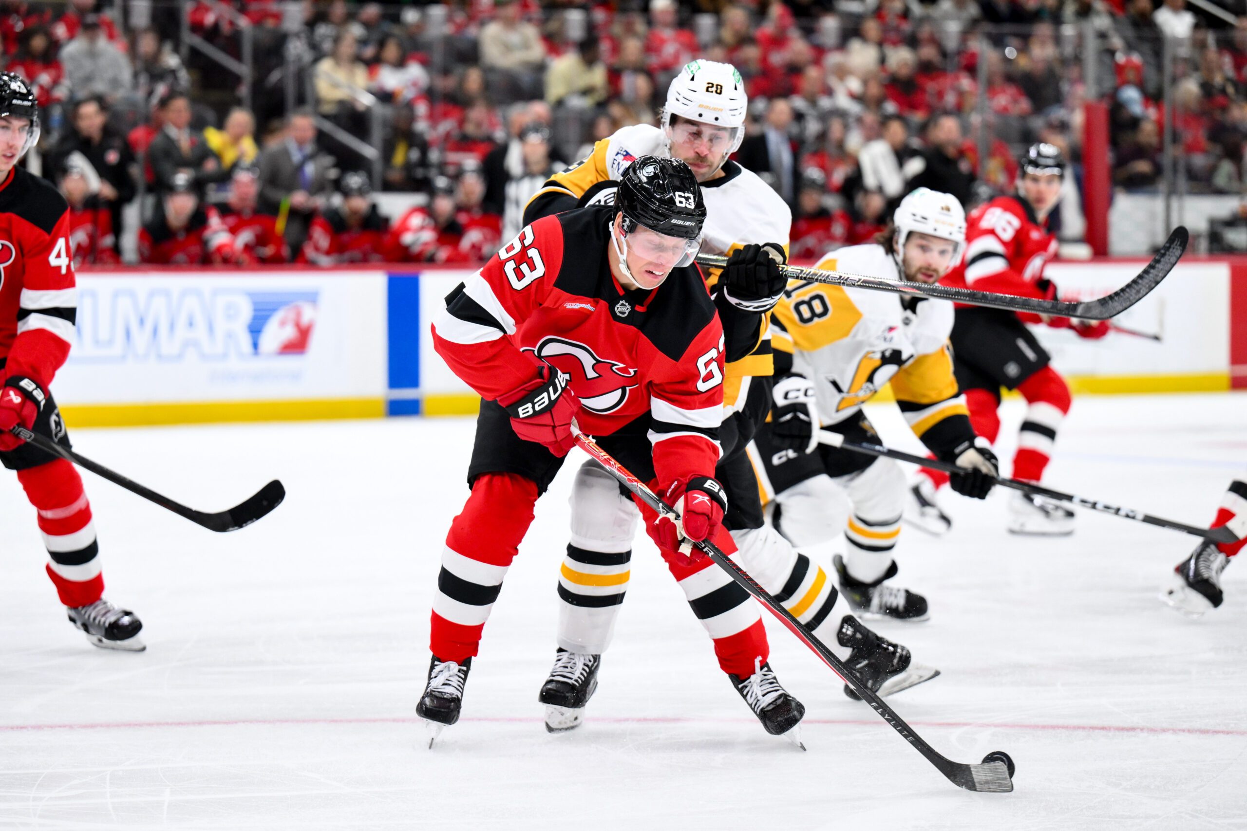Nov 8, 2025; Newark, New Jersey, USA; New Jersey Devils left wing Jesper Bratt (63) skates with the puck while defended by Pittsburgh Penguins defenseman Parker Wotherspoon (28) during the first period at Prudential Center. Mandatory Credit: John Jones-Imagn Images