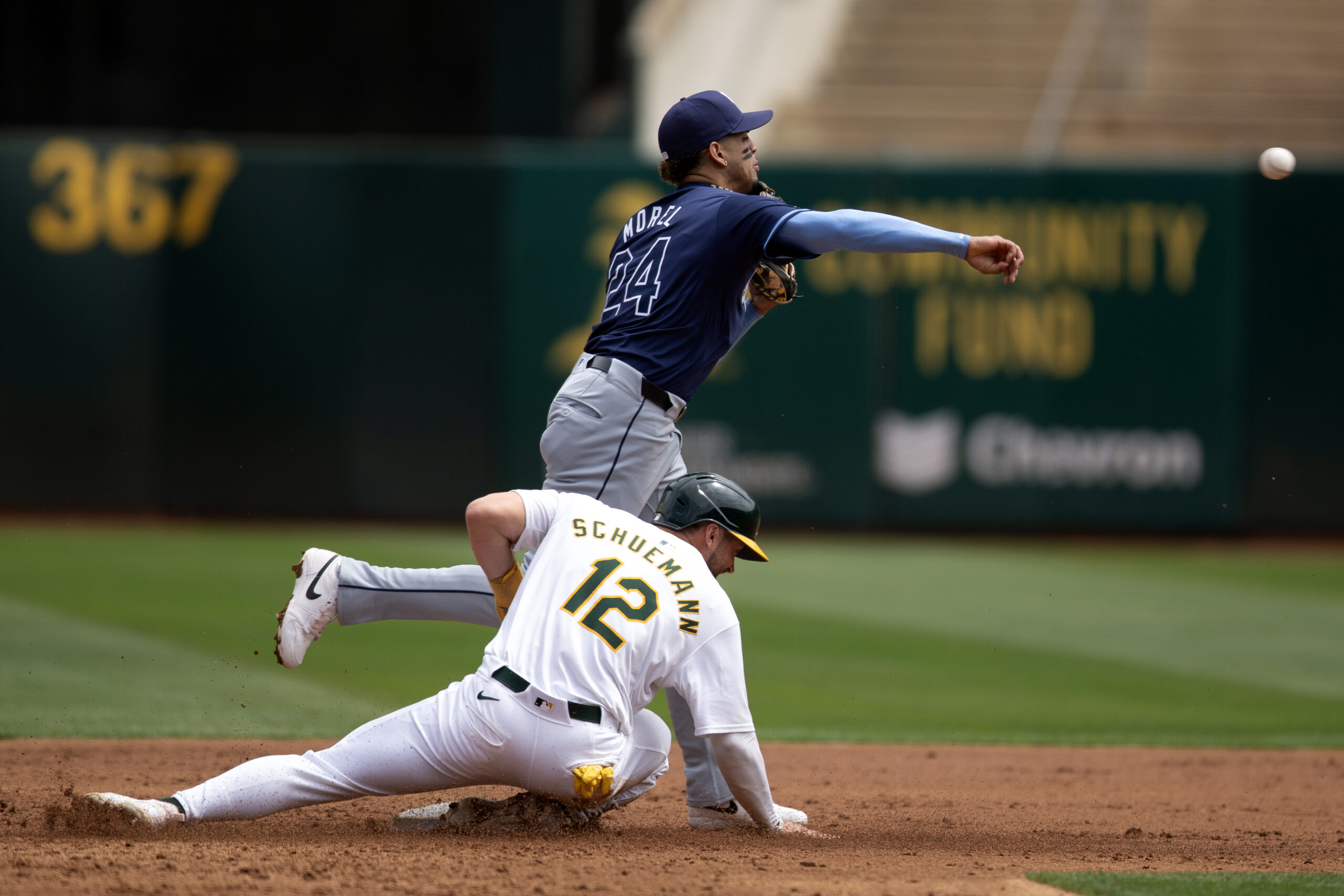 Aug 22, 2024; Oakland, California, USA; Tampa Bay Rays second baseman Christopher Morel (24) throws over Oakland Athletics shortstop Max Schuemann (12) to complete a double play during the second inning at Oakland-Alameda County Coliseum. Mandatory Credit: D. Ross Cameron-Imagn Images