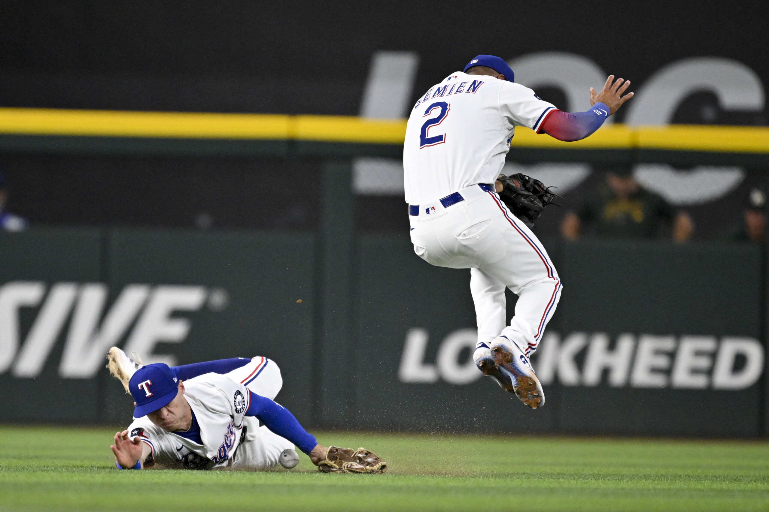 Jul 23, 2025; Arlington, Texas, USA; Texas Rangers center fielder Michael Helman (24) dives but cannot catch a ball hit by Athletics left fielder Miguel Andujar (not pictured) as second baseman Marcus Semien (2) attempts to get out of way during the sixth inning at Globe Life Field. Mandatory Credit: Jerome Miron-Imagn Images