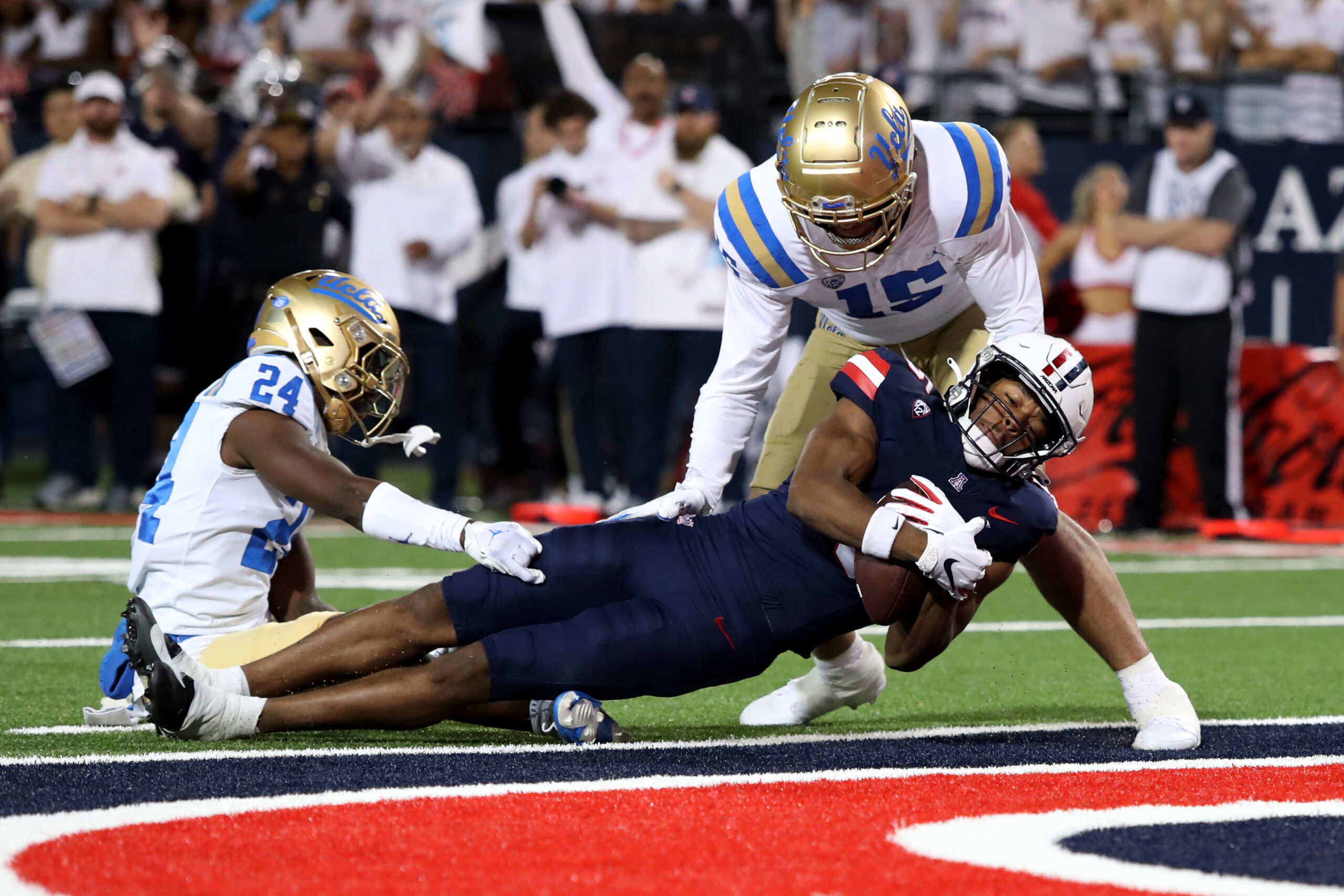 Nov 4, 2023; Tucson, Arizona, USA; Arizona Wildcats wide receiver Montana Lemonious-Craig #5 dives into the endzone against UCLA Bruins defensive back Jaylin Davies #24 and defensive lineman Laiatu Latu #15 during the first half at Arizona Stadium. Mandatory Credit: Zachary BonDurant-Imagn Images