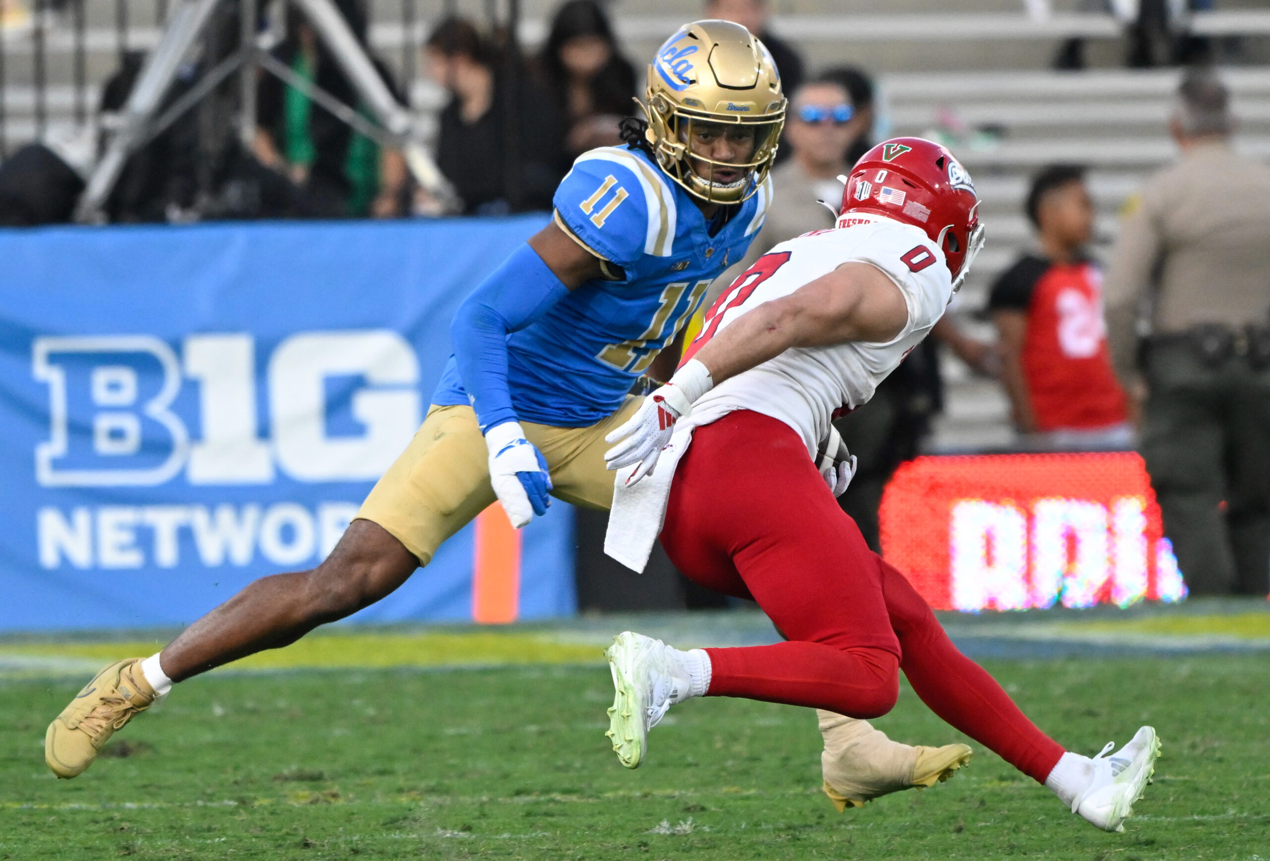 Nov 30, 2024; Pasadena, California, USA; UCLA Bruins defensive back Ramon Henderson (11) moves in to tackle Fresno State Bulldogs wide receiver Mac Dalena (0) during the fourth quarter at Rose Bowl. Mandatory Credit: Robert Hanashiro-Imagn Images
