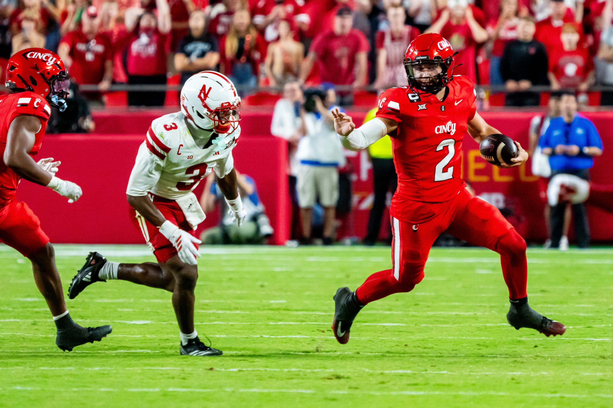 Aug 28, 2025; Kansas City, Missouri, USA; Cincinnati Bearcats quarterback Brendan Sorsby (2) scrambles against Nebraska Cornhuskers defensive back Marques Buford Jr. (3) during the fourth quarter at GEHA Field at Arrowhead Stadium. Mandatory Credit: Dylan Widger-Imagn Images
