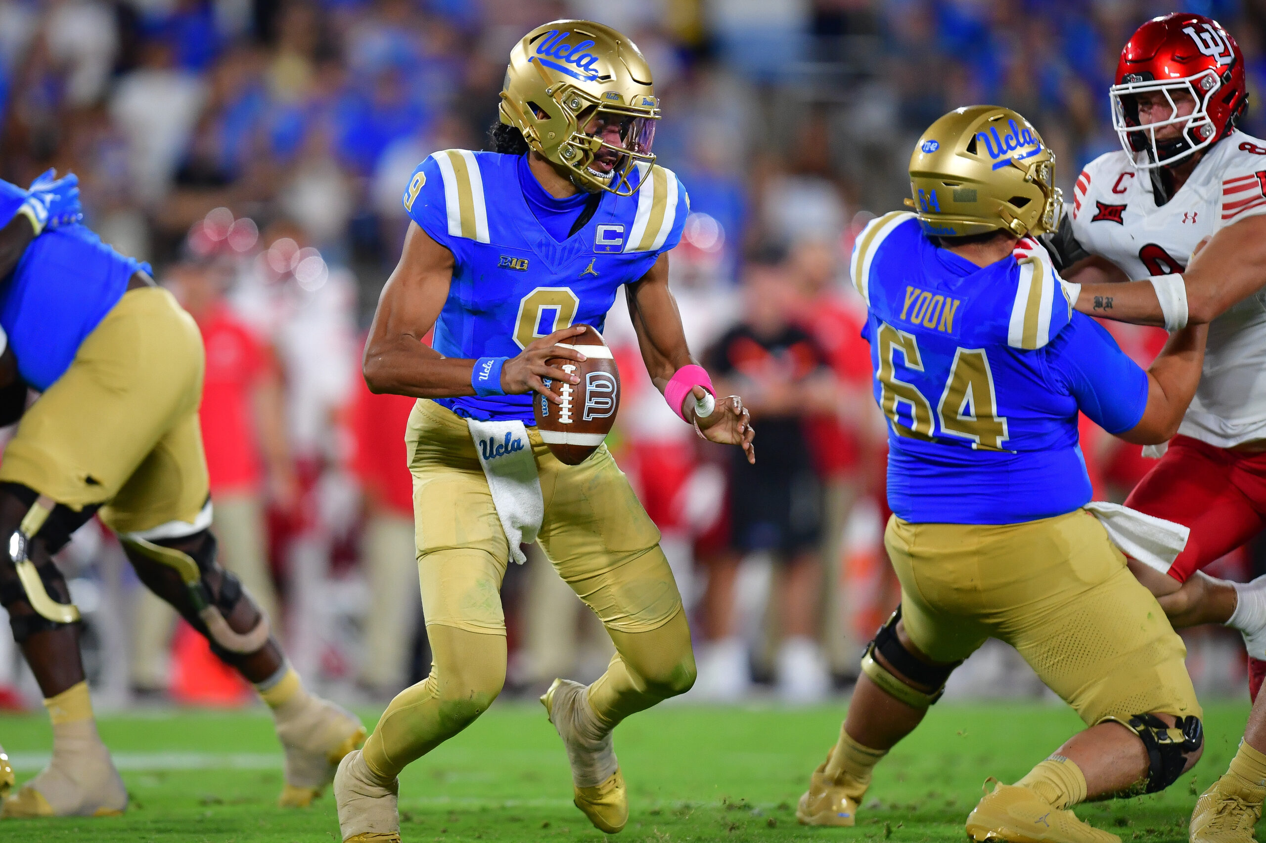 Aug 30, 2025; Pasadena, California, USA; UCLA Bruins quarterback Nico Iamaleava (9) moves out to pass as offensive lineman Sam Yoon (64) provides coverage against Utah Utes linebacker Lander Barton (8) during the second half at Rose Bowl. Mandatory Credit: Gary A. Vasquez-Imagn Images
