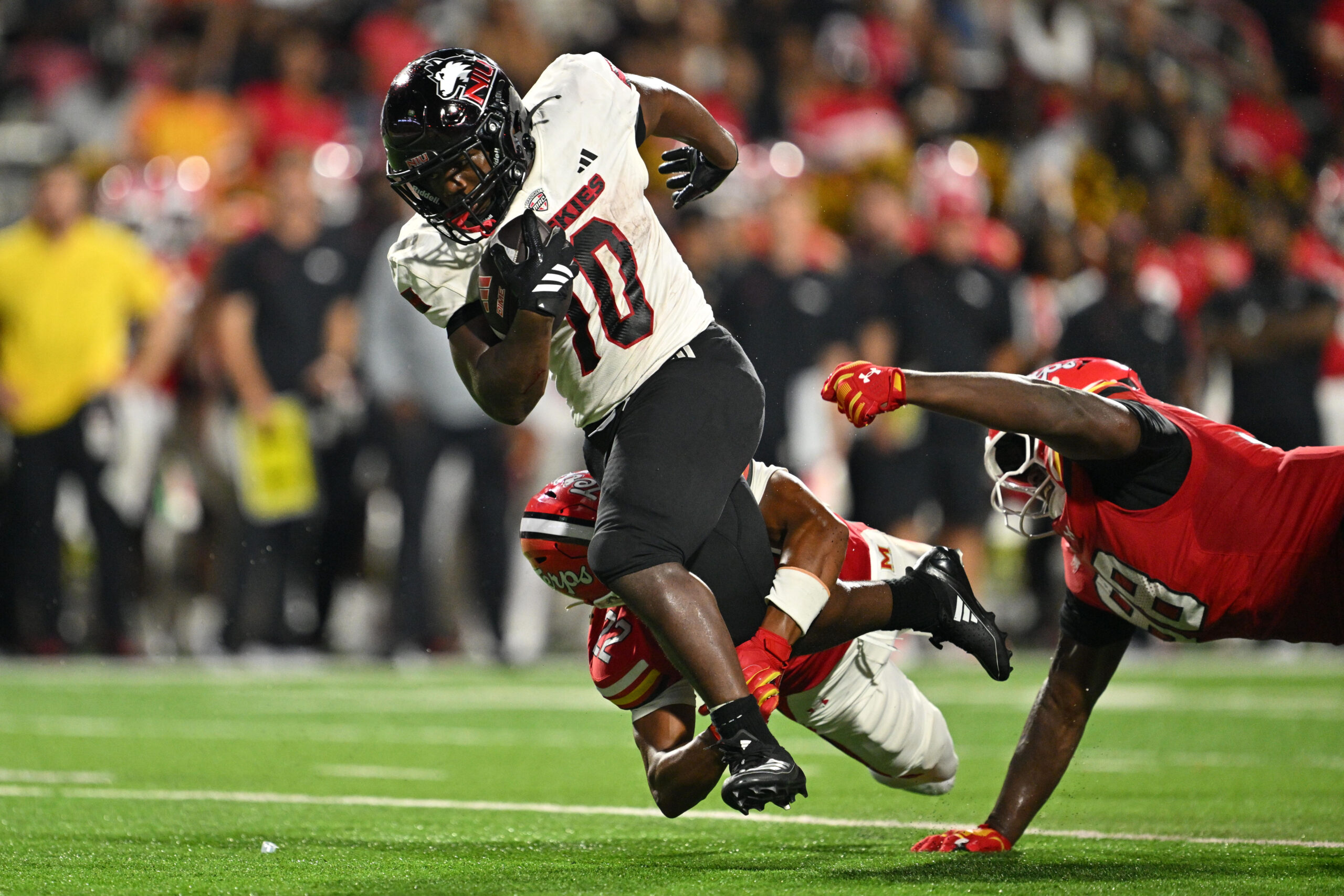 Sep 5, 2025; College Park, Maryland, USA;  Northern Illinois Huskies running back Chavon Wright (10) is tripped up by Maryland Terrapins defensive back Jalen Huskey (22) after picking up a first down in the first half at SECU Stadium. Mandatory Credit: Jamie Sabau-Imagn Images