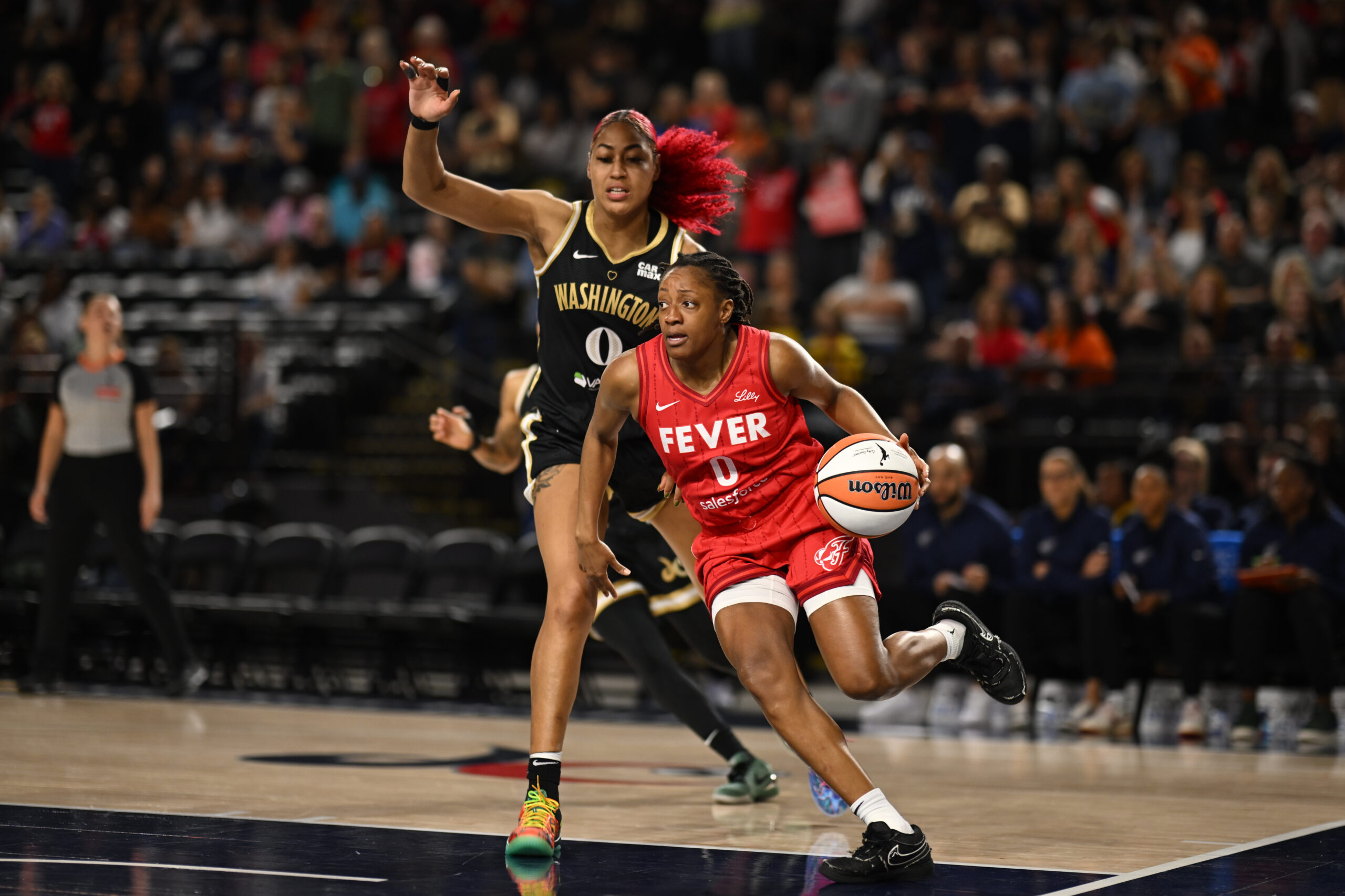 Sep 7, 2025; Baltimore, MD, USA; Indiana Fever guard Kelsey Mitchell (0) drives to the basket in front of Washington Mystics forward Shakira Austin (0) during the first quarter at CFG Bank Arena. Mandatory Credit: Rafael Suanes-Imagn Images